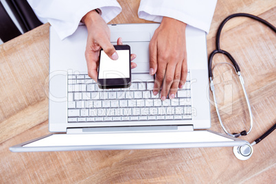 Doctor using smartphone on wooden desk