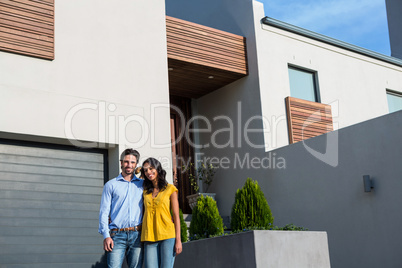 Happy couple standing in front of new house