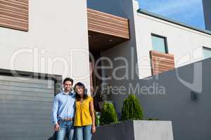 Happy couple standing in front of new house