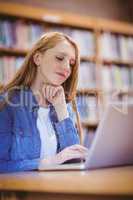 Focused student using laptop in library