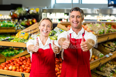 Smiling couple showing thumbs and wearing apron