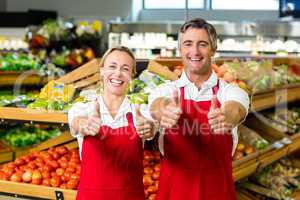 Smiling couple showing thumbs and wearing apron