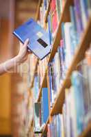 Students hand with smartwatch picking book from bookshelf