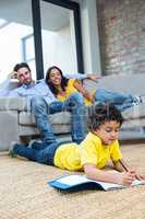 Smiling family on living room with son drawing