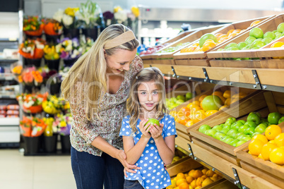 Daughter holding an apple at grocery shop