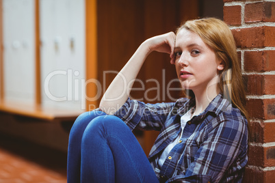 Thoughtful student sitting on the floor against the wall and loo