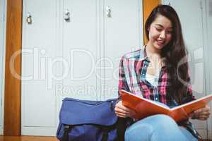 Smiling student sitting and reading a notebook