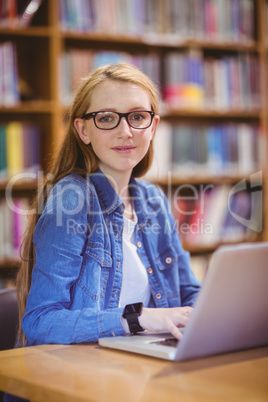 Student with smartwatch using laptop in library