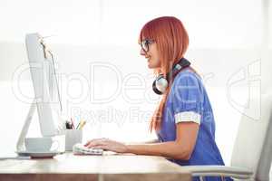 Smiling hipster woman typing on keyboard