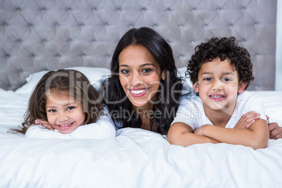 Smiling mother with children on the bed