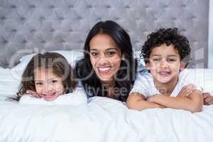 Smiling mother with children on the bed