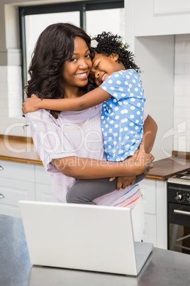 Mother using laptop while carrying kid