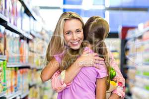 Smiling mother and daughter with grocery bag hugging