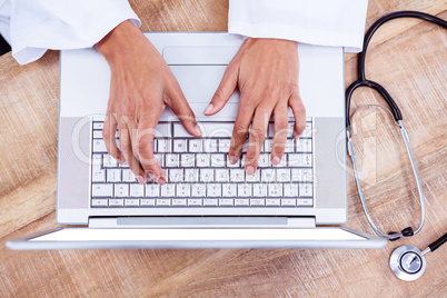 Doctor using laptop on wooden desk