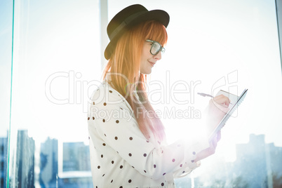 Smiling hipster woman writing notes