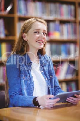 Student with smartwatch using tablet in library