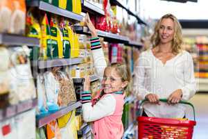 Cute daughter taking food from shelf