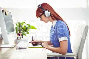 Attractive hipster woman with headset using graphics tablet