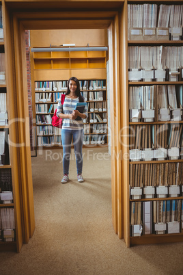 Pretty student standing in library holding a book Pretty student standing in library holding a book