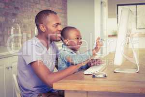 Cute son using laptop at desk with father