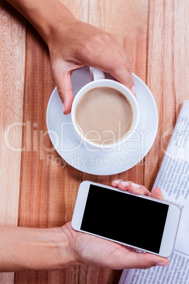 Part of hands holding coffee and smartphone