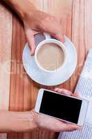 Part of hands holding coffee and smartphone