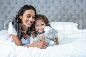 Happy mother and daughter laying o the bed