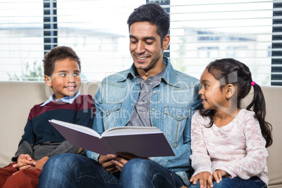 Happy father reading a book for his children