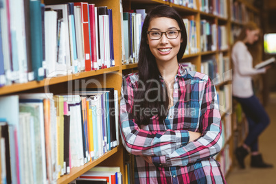 Smiling student leaning against bookshelves