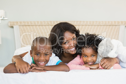 Mother and children lying on bed