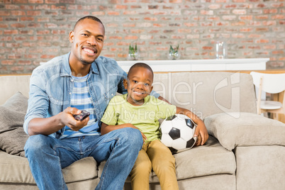 Father and son watching tv together on the couch