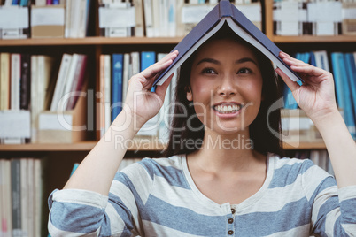 Funny student holding book on her head