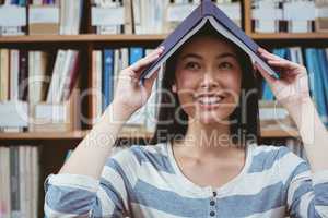 Funny student holding book on her head