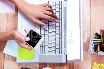 Overhead of feminine hands using laptop and smartphone