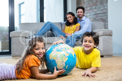 Children holding globe on carpet in living room