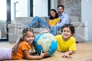 Children holding globe on carpet in living room