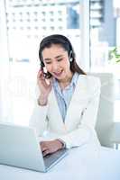 Smiling businesswoman with headset using laptop