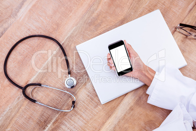 Doctor using smartphone on wooden desk