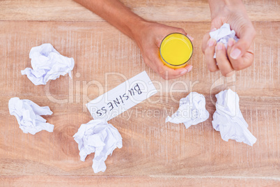Businesswoman having orange juice and holding crumpled paper