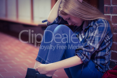 Thoughtful student sitting on the floor against the wall