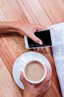 Part of hands holding coffee and smartphone