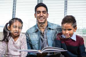 Happy father reading a book for his children