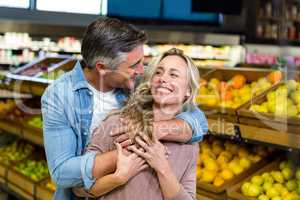 Smiling couple hugging in fruit aisle