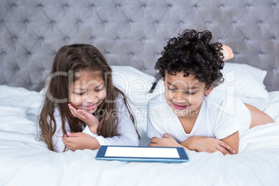 Cute siblings using tablet on the bed