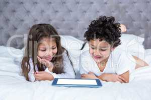 Cute siblings using tablet on the bed