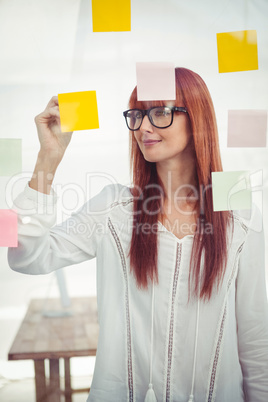 Attractive hipster woman writing on sticky notes