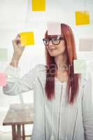 Attractive hipster woman writing on sticky notes