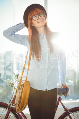 Smiling hipster woman leaning on a bike