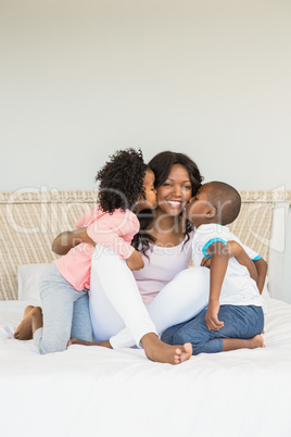 Children kissing mother on bed