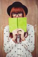 Hipster woman behind a green book